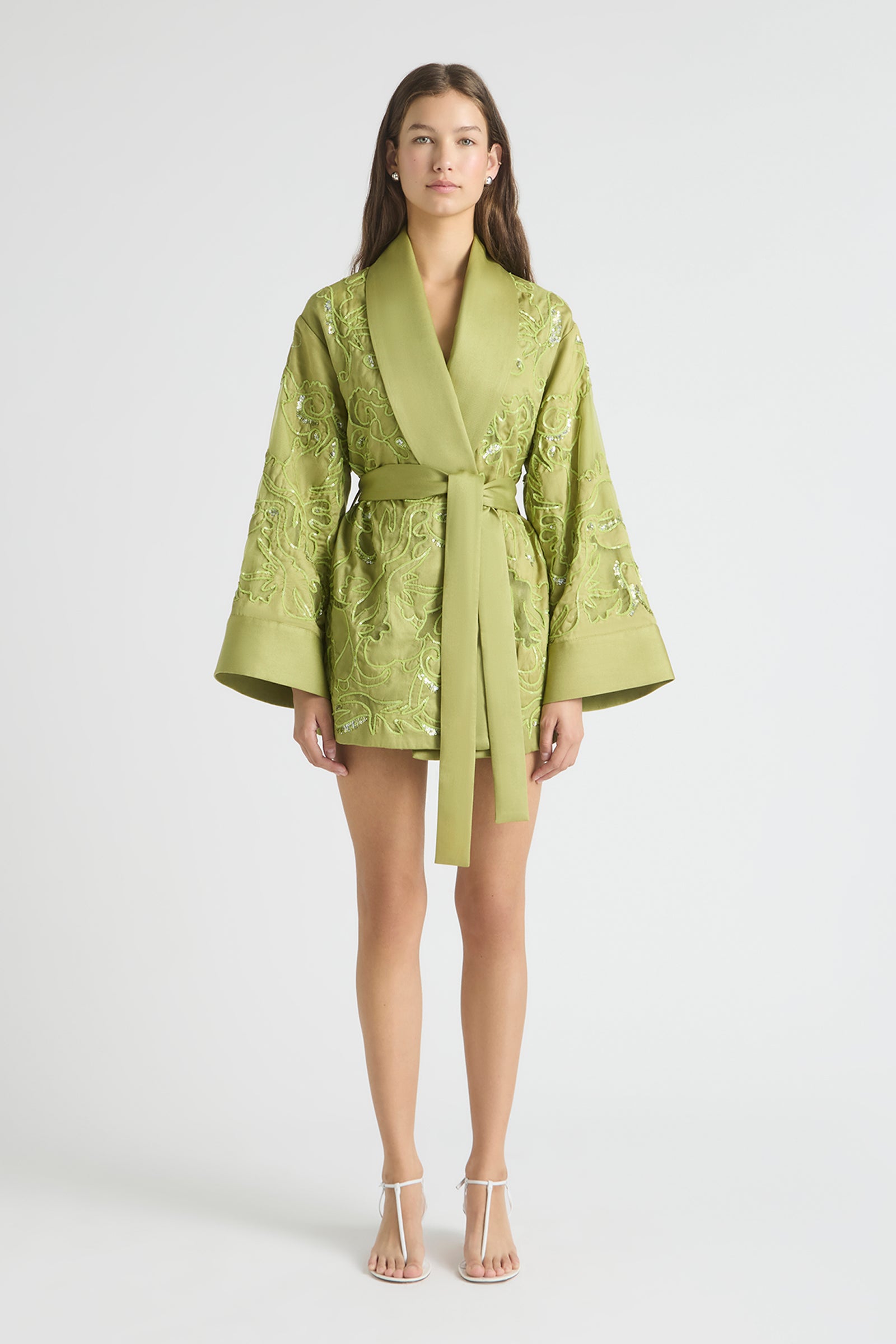 Woman wearing a green embroidered robe on a white background